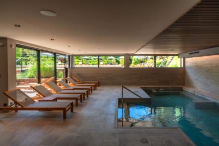 Piscine intérieure du Spa Caudalie au Château de Germigney avec espace de détente et transats.