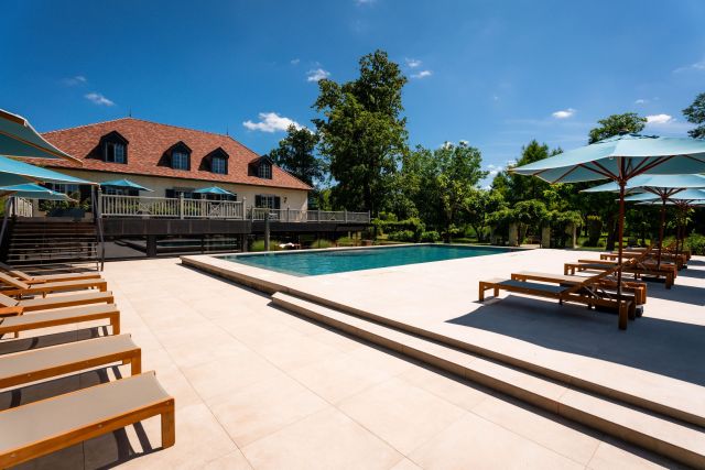 Piscine extérieure du Château de Germigney avec transats et parasols au cœur du parc.