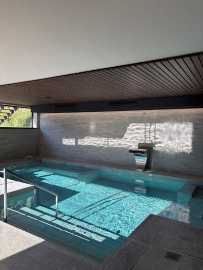 Piscine intérieure du Spa Caudalie au Château de Germigney avec espace de détente et transats.